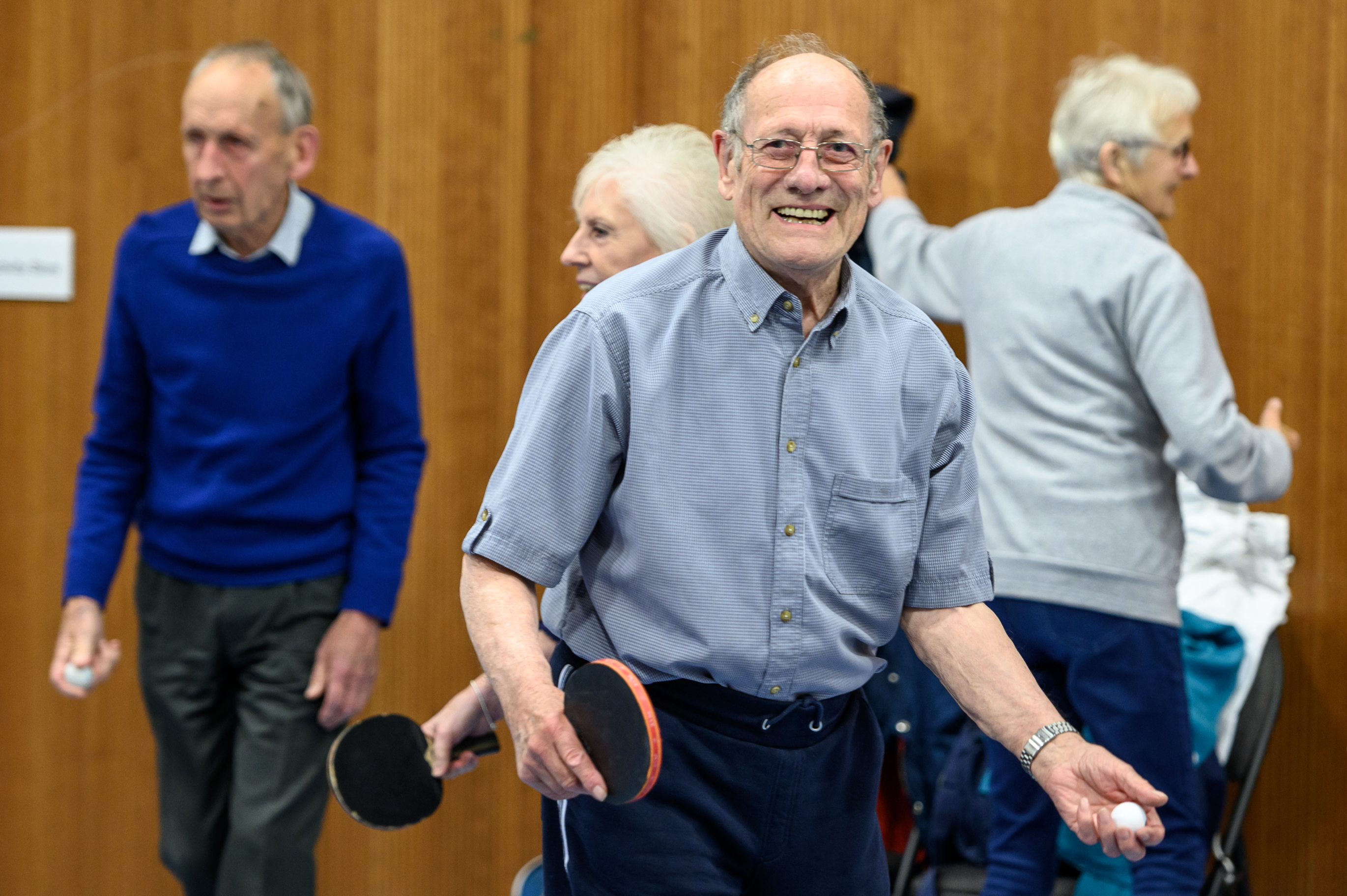 Older man smiling whilst playing table tennis