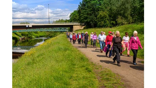 Large group walk along the bank of a river