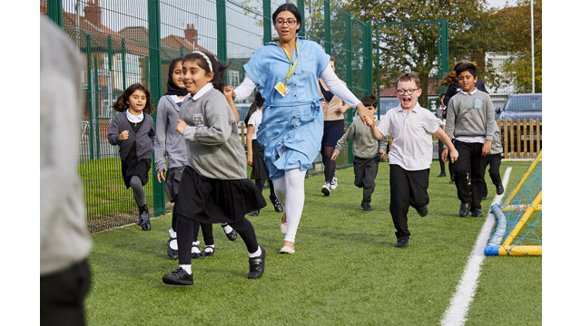 Teacher and schoolchildren running around taking part in The Daily Mile