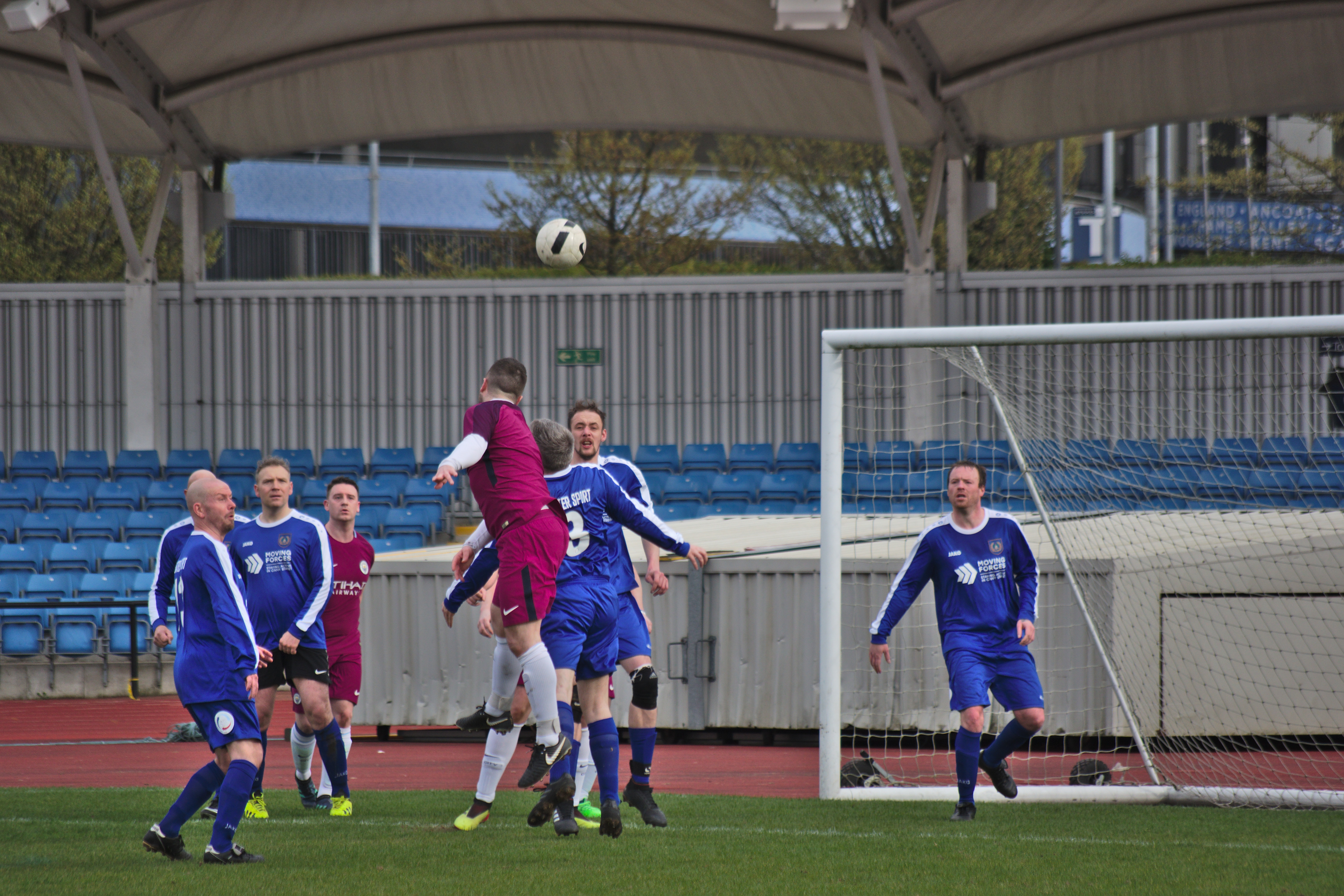 Man jumping over players to head the ball into the goal during a football match