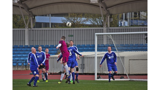 Man jumping over players to head the ball into the goal during a football match