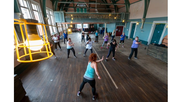 Overhead view of a group dance exercise class in a community centre