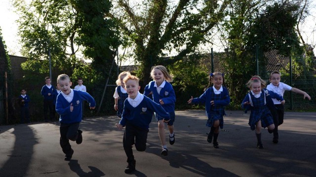 Schoolchildren running around their playground doing The Daily Mile