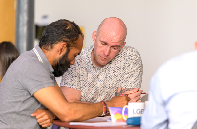 Two men sat at a table doing paperwork