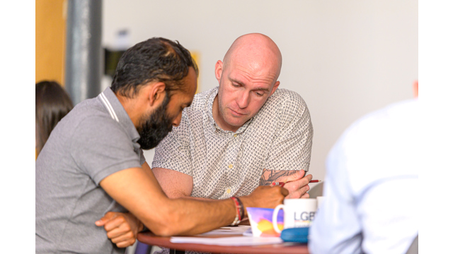 Two men sat at a table doing paperwork