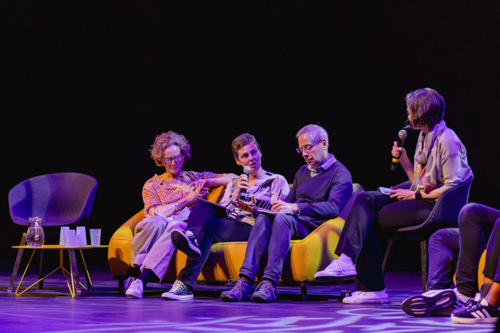 Four people seated on a conference stage, mid discussion