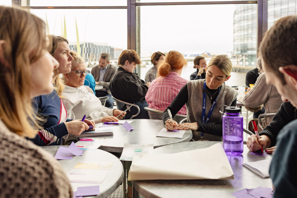 Somebody writing down notes in a bright room during a conference discussion