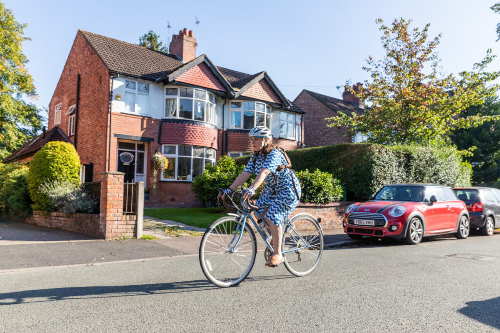 Someone cycling along a suburban road in the sunshine