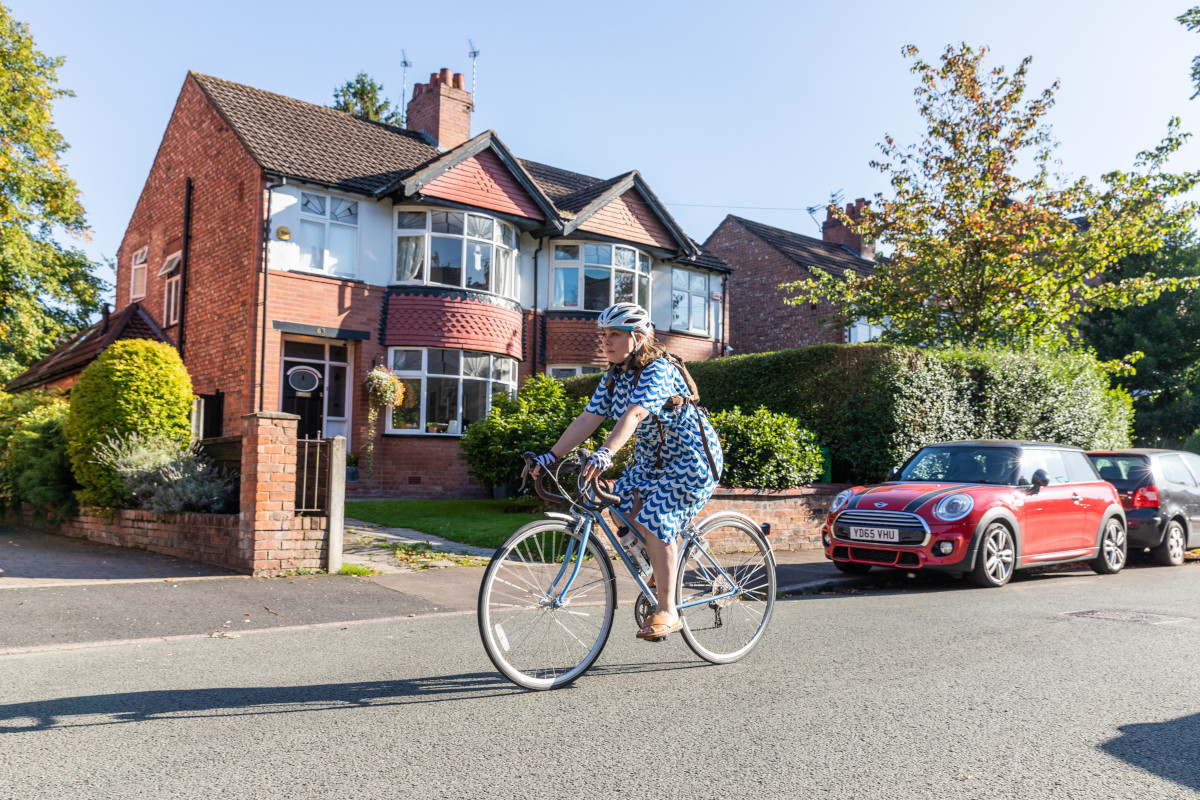 Someone cycling along a suburban road in the sunshine