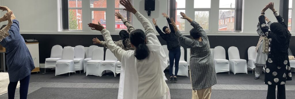 A group of women do yoga together in a light community room.