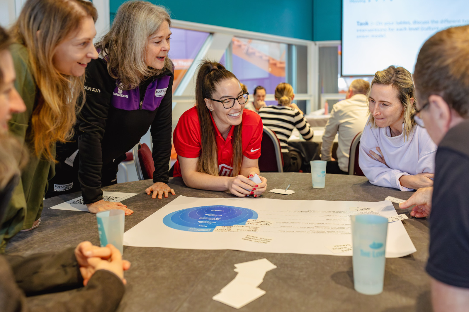 A group of people lean over a table in casual discussion