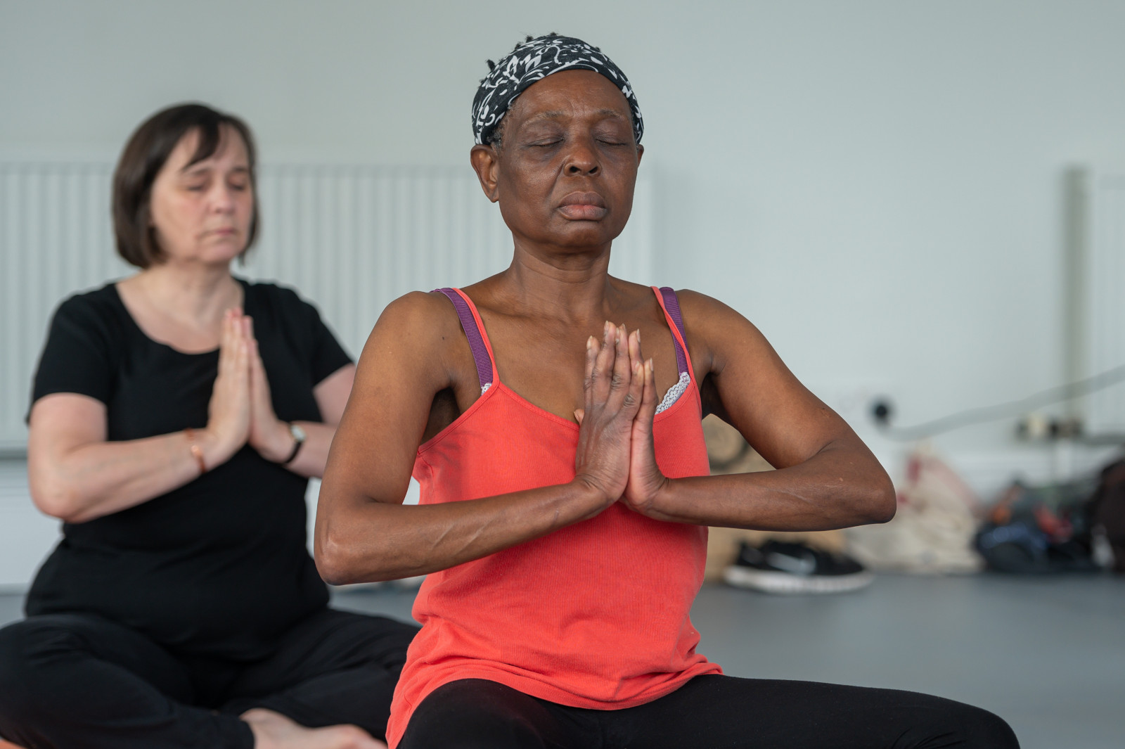 A person sitting crossed legged on the floor, eyes closed, meditating