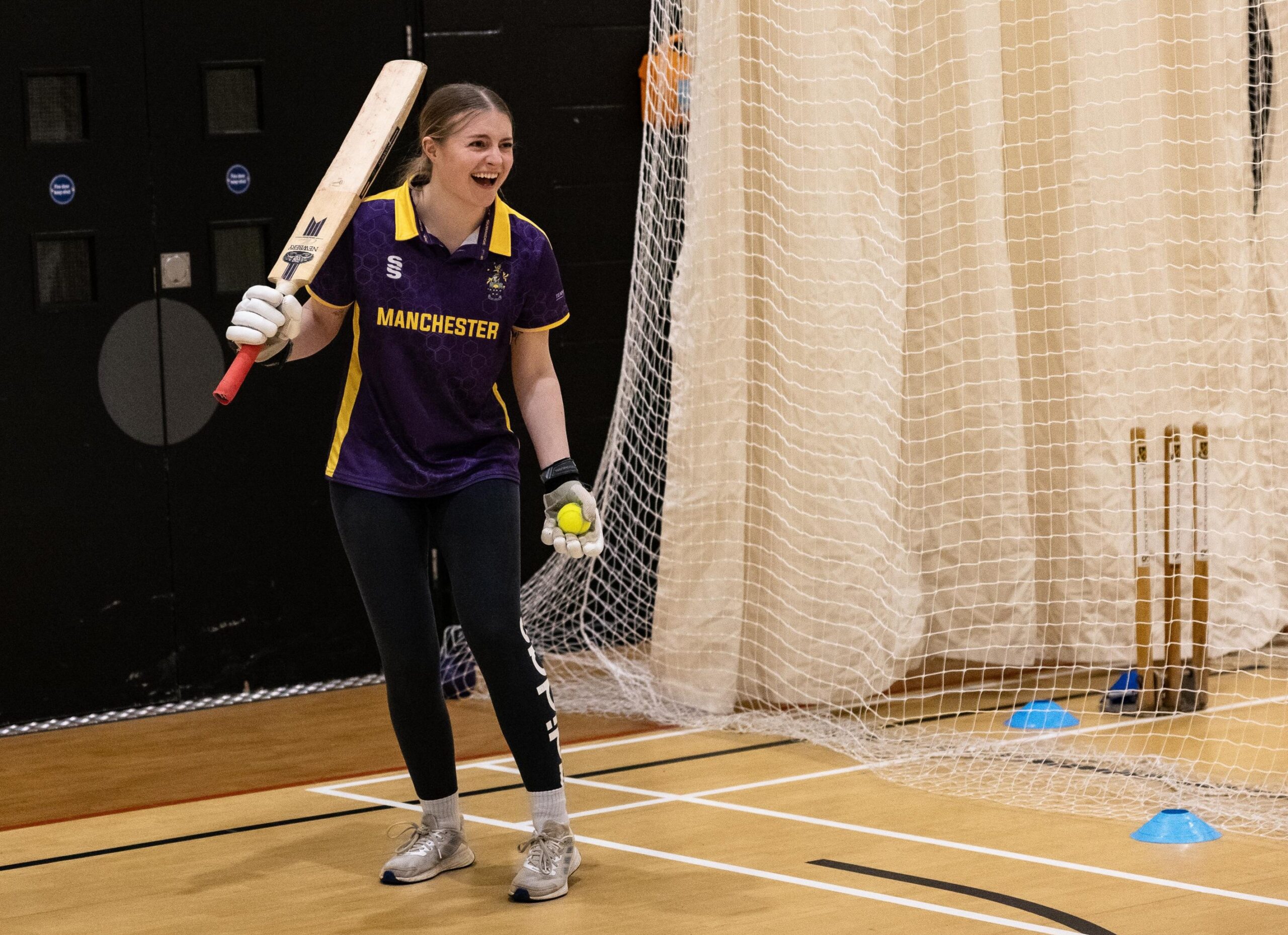 Someone playing cricket indoors, laughing