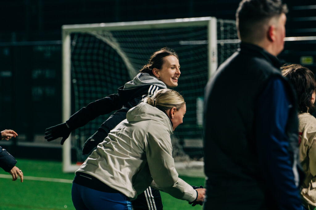 Two people playing football at night and smiling