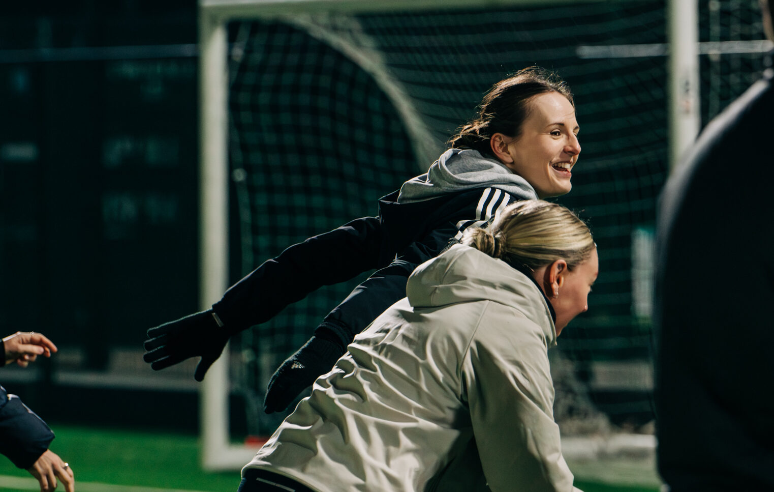 Two people playing football at night and smiling