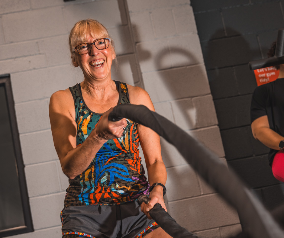 photo of sue waring - women smiling doing a gym exercise battle ropes