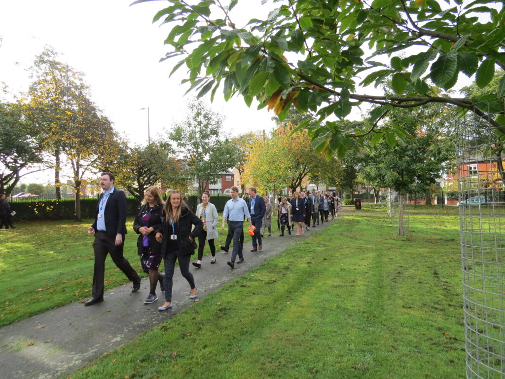 A group of colleagues walk through a green park on a sunny day