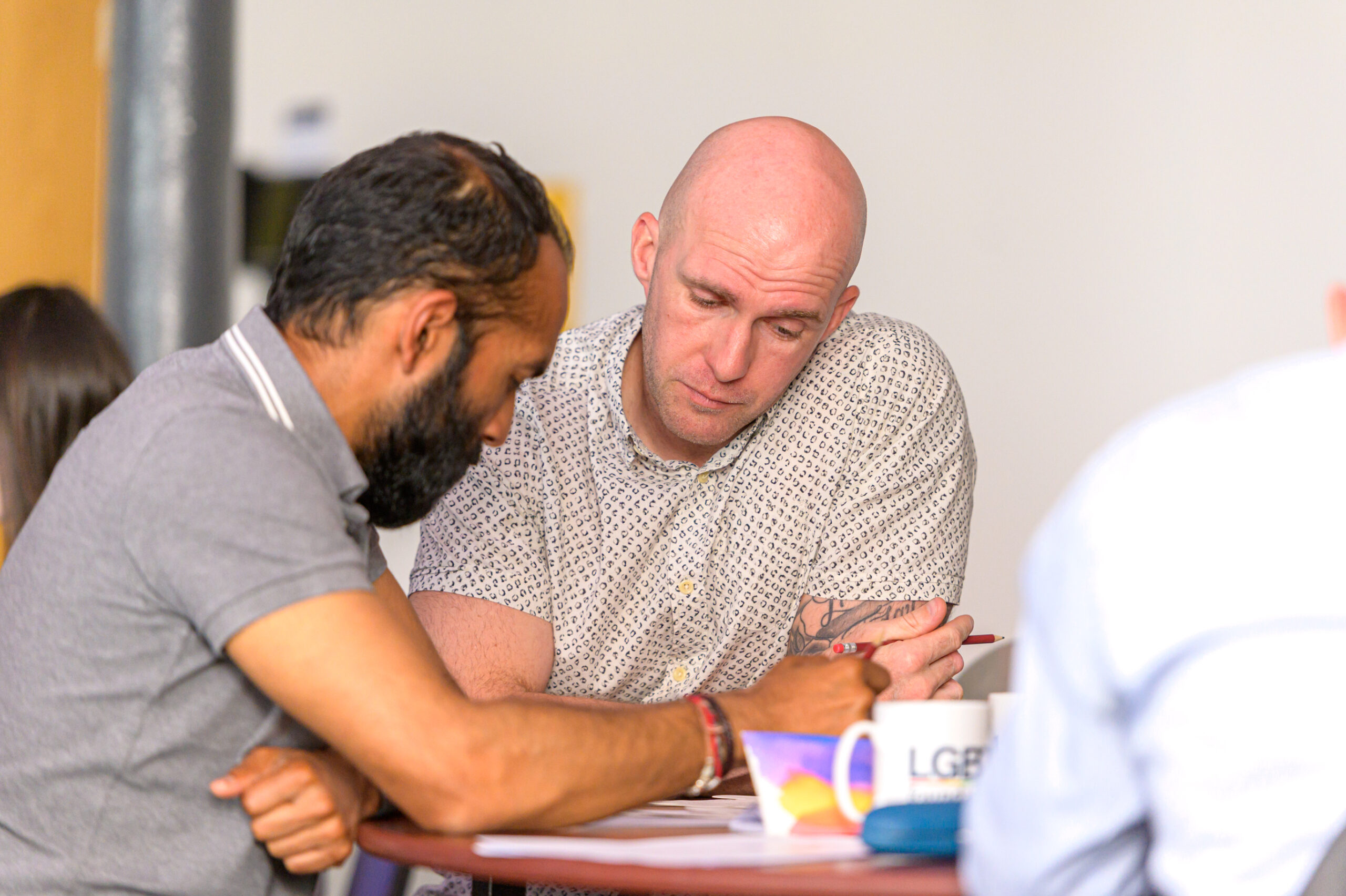 Two people discuss workshop materials while sat around a table