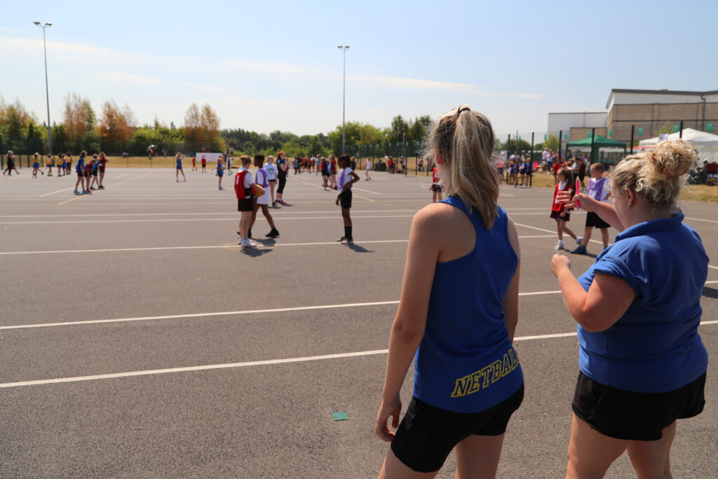 A group of young people watch others play sport on an outdoor track