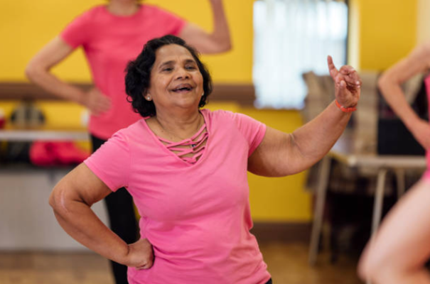 An adult dances in a group class while smiling