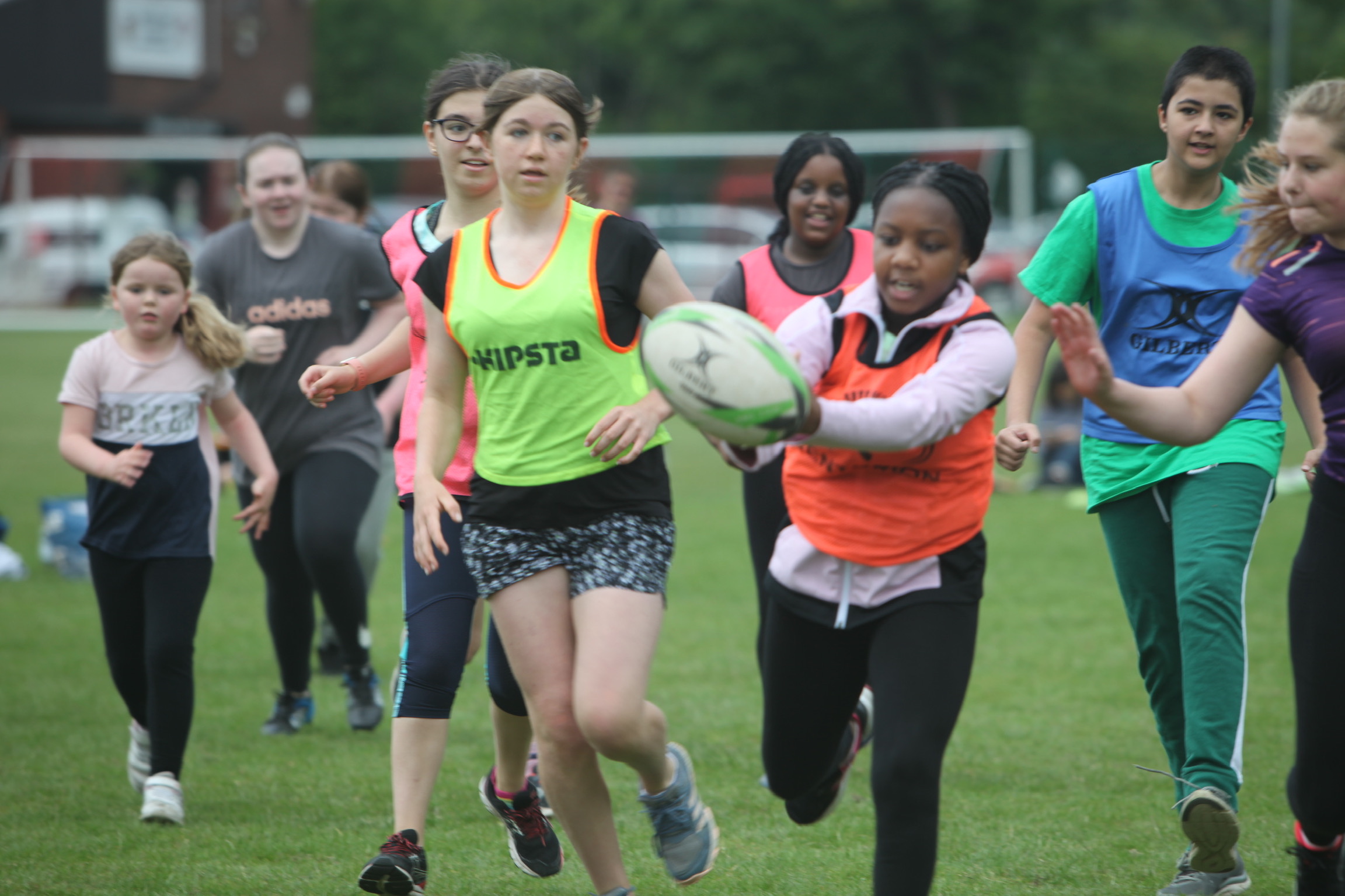 Children running towards camera chasing a rugby ball.