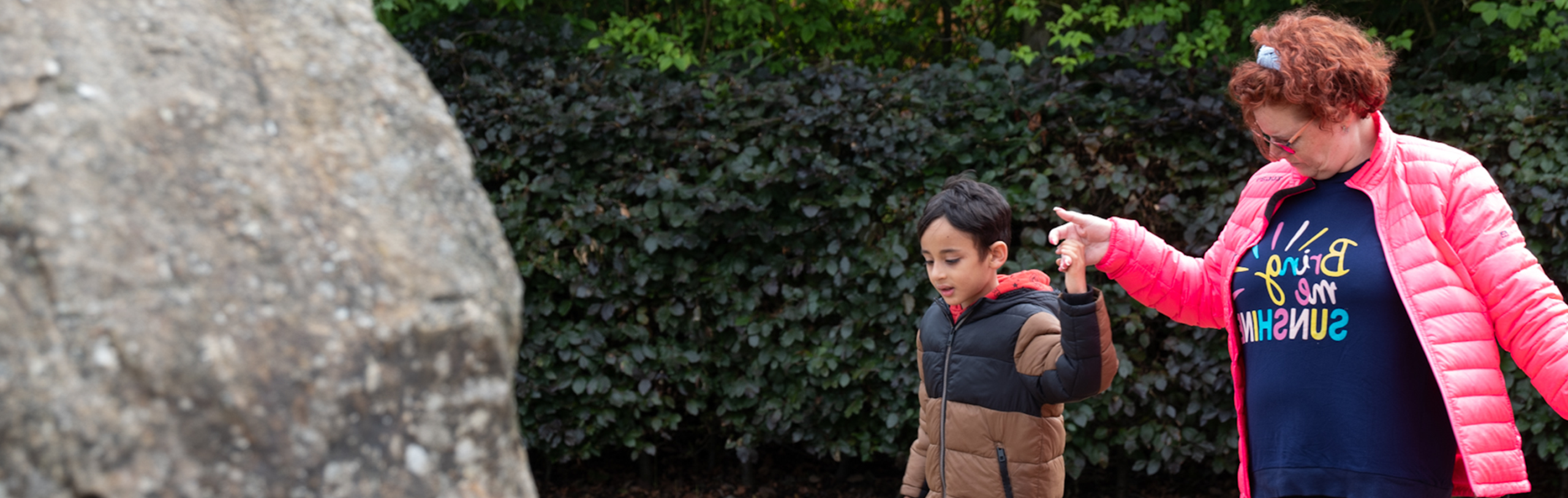 An adult and a child walking outdoors, holding hands