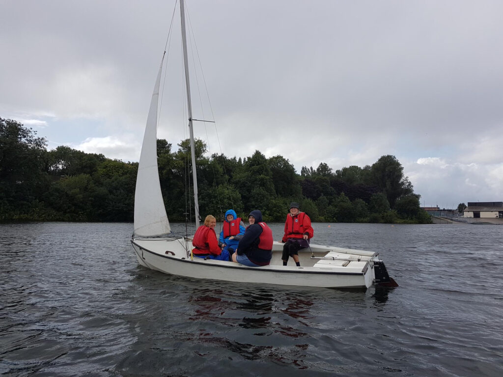 A group of smiling women enjoying sailing on a lake