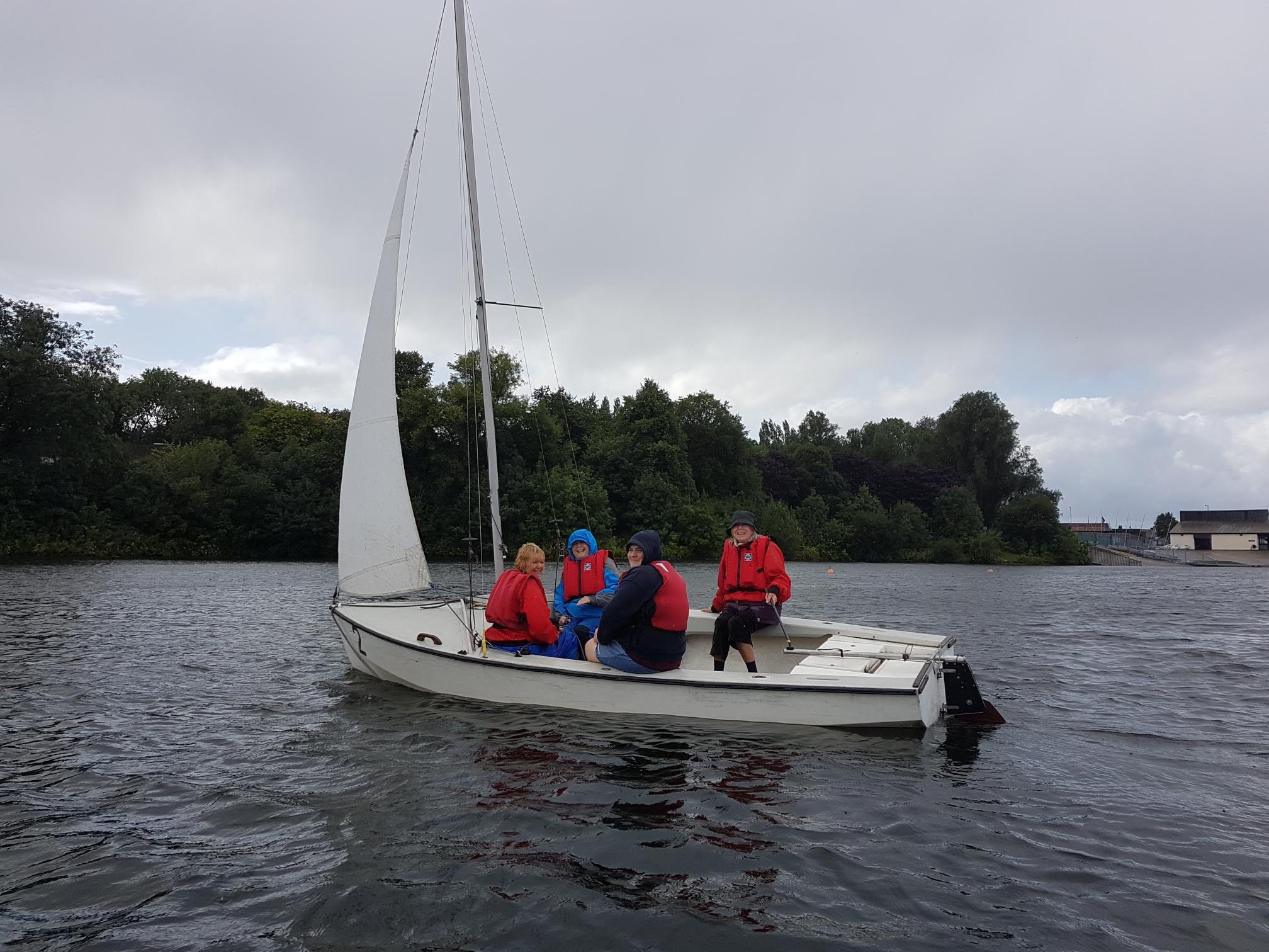 A group of smiling women enjoying sailing on a lake