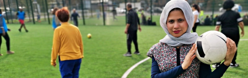 A person in a hijab holding a football and looking into camera
