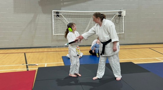 A tutor and a child practice moves in a dojo